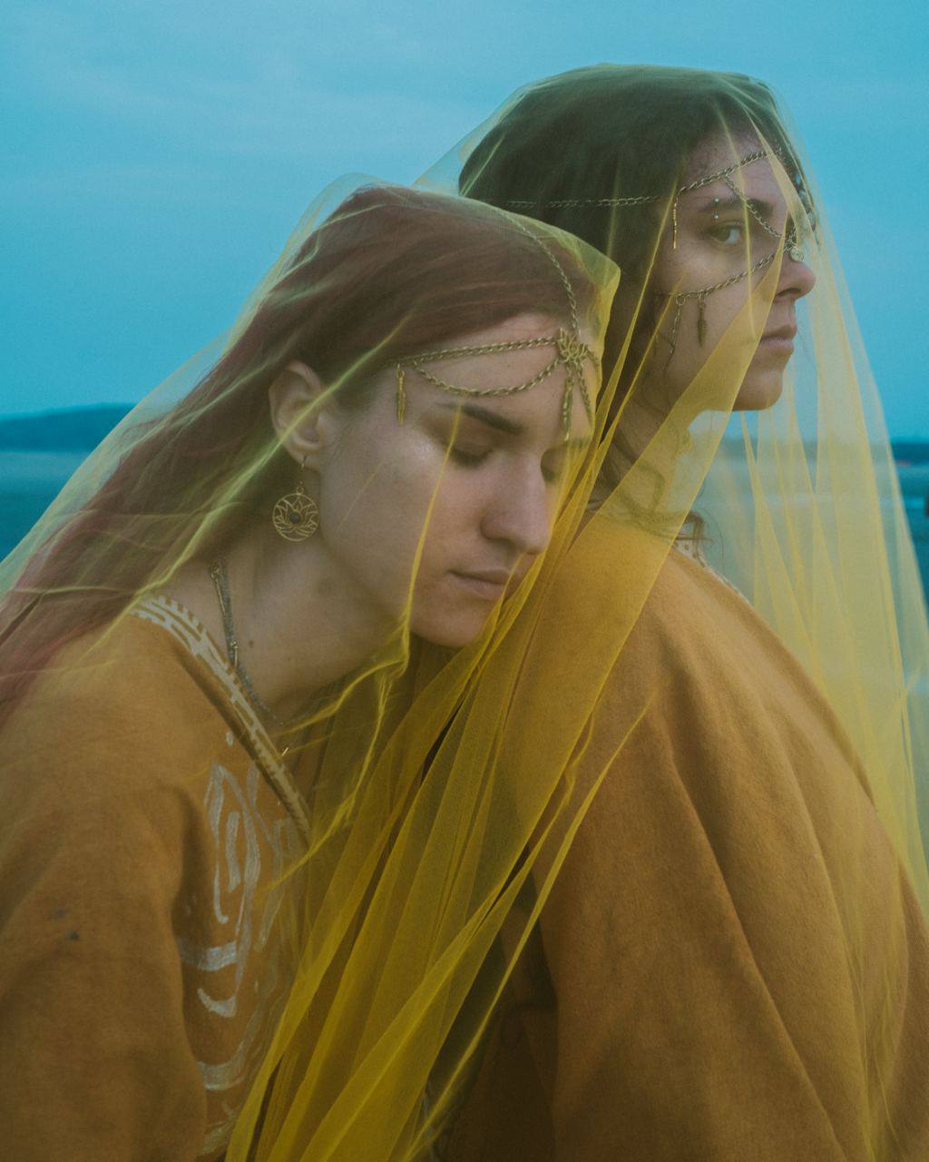 Group portrait of two women wearing gold headchains under yellow veil
